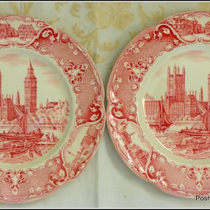 Puede incluir: Dos platos de cerámica blanca con un diseño rojo del Parlamento de Londres. Los platos tienen un borde festoneado y un delicado patrón floral.