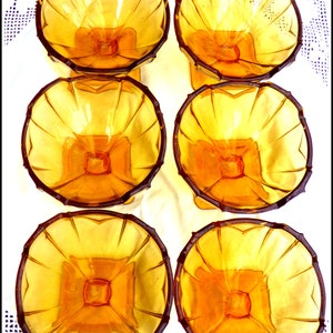 May include: Six amber glass dessert bowls with a fluted design. The bowls are arranged in two rows of three.