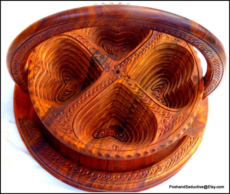 May include: A wooden serving tray with four heart-shaped compartments. The tray has a handle and is intricately carved with floral designs.