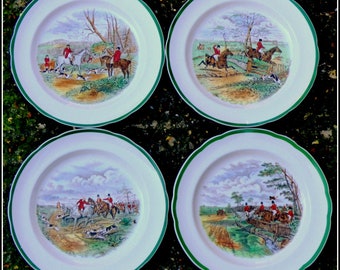 May include: Set of four white ceramic plates with green trim. Each plate features a colorful illustration of a hunting scene with riders on horseback.