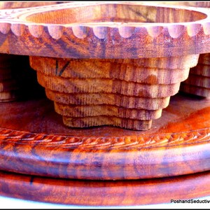 May include: A wooden serving tray with two carved bowls. The tray is made of dark wood with a reddish hue and has a decorative carved border. The bowls are also made of dark wood and have a layered, tiered design.