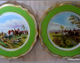 May include: Two antique porcelain plates with green and gold trim. Each plate features a hand-painted scene of a fox hunt with riders on horseback.