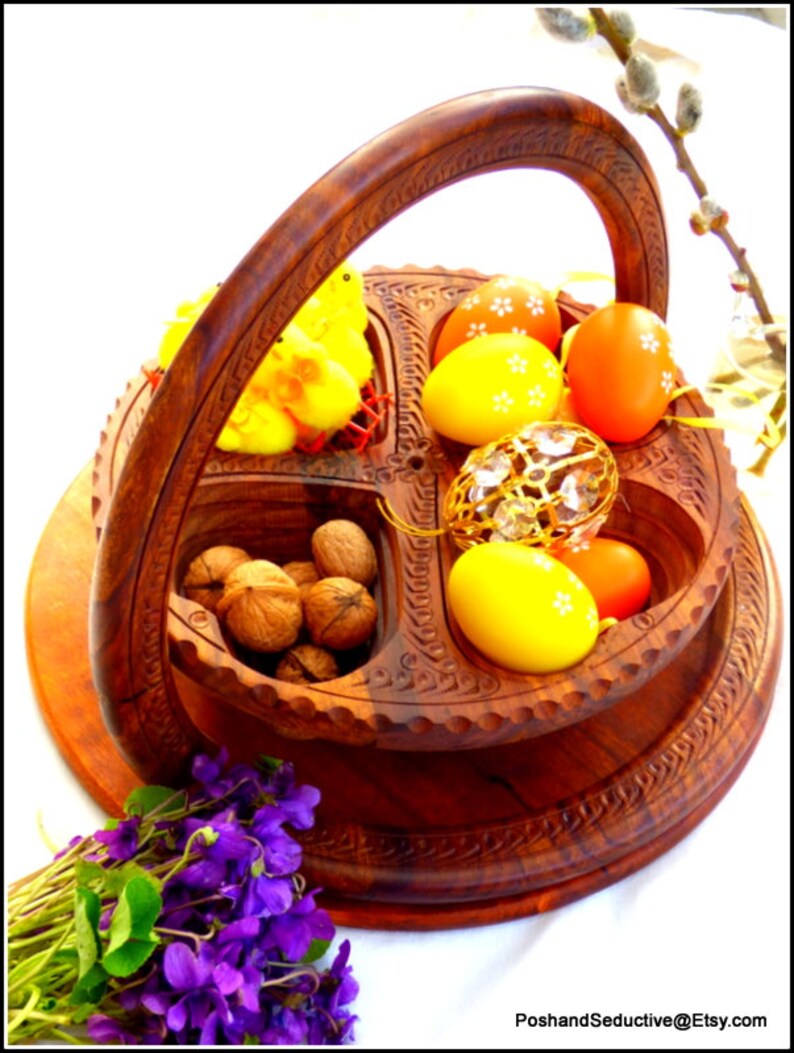 May include: A wooden serving tray with four compartments, featuring a carved design. The tray holds yellow chicks, decorated Easter eggs, walnuts, and a crystal ornament. The tray is on a wooden base with a handle.