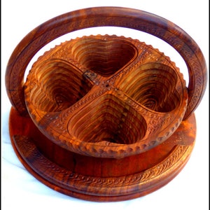 May include: A wooden serving tray with four heart-shaped compartments. The tray has a carved handle and intricate details.