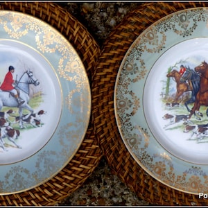 May include: Two vintage ceramic plates with a green and gold border. The plates feature a hunting scene with riders on horseback and hounds chasing a fox.
