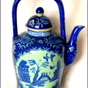 May include: A blue and white porcelain teapot with a lid and a handle. The teapot features a floral design and a scene of a pagoda and a tree.