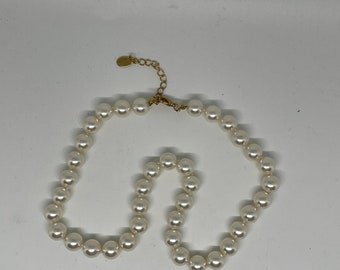 May include: A white pearl necklace with a gold clasp. The necklace is made of faux pearls and is approximately 18 inches long.