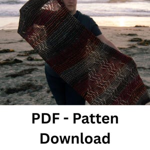 Op de afbeelding: Een gebreide sjaal met een geometrisch patroon in tinten rood, bruin en grijs. De sjaal wordt getoond tegen een strandachtergrond. De tekst "PDF - Pattern Download" staat onderaan de afbeelding.