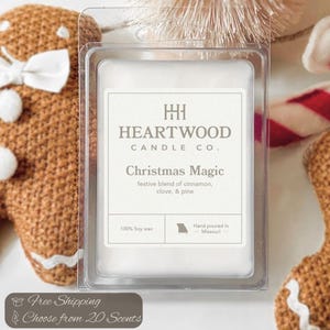 May include: A clear plastic package contains a white wax melt with the text "Christmas Magic" and "Heartwood Candle Co." The scent is a festive blend of cinnamon, clove, and pine. The package is surrounded by gingerbread men and a candy cane.