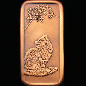 May include: A copper-colored rectangular plaque with a raised image of a fox sitting under a branch with leaves. The fox is facing to the right and has a bushy tail.