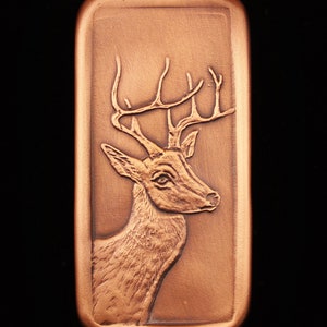 May include: A copper-colored rectangular plaque with a detailed embossed image of a deer's head with antlers.