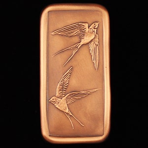 May include: A rectangular copper plaque with two stylized swallows in flight. The swallows are facing opposite directions and are in a raised relief design.