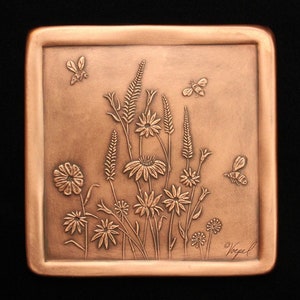 May include: A copper-colored square plaque with an embossed design of wildflowers and bees. The plaque is signed "Voepel" in the lower right corner.