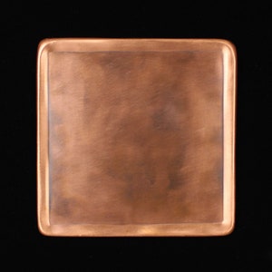 May include: A square copper tray with a slightly hammered finish. The tray has a raised edge and a smooth, polished surface.