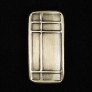 May include: A rectangular, antique brass-colored cabinet pull with a grid-like design. The pull features a series of horizontal and vertical lines, creating a segmented appearance. The metal has a slightly textured surface and a vintage aesthetic.