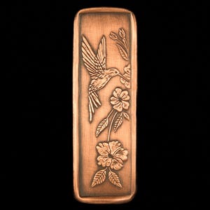 May include: A copper-colored rectangular bookmark with an engraved design of a hummingbird feeding from a flower.
