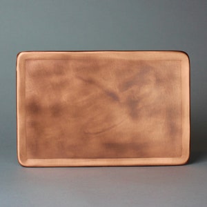 May include: A rectangular copper tray with a slightly textured surface. The tray has a raised edge around the perimeter.