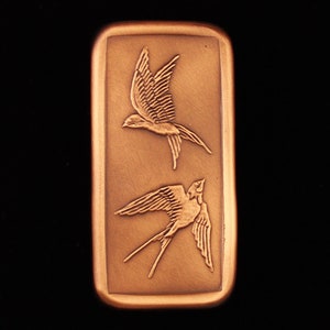 May include: A rectangular copper bar with two stylized swallows in relief. The swallows are facing opposite directions, one flying upwards and the other flying downwards.