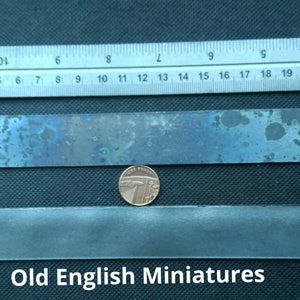 May include: Two metal strips, one with a blue-grey patina and the other with a smooth, polished finish, are shown next to a ruler and a British one-pound coin. The text "Old English Miniatures" is printed below the strips.