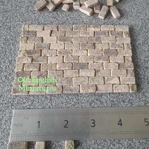 May include: Miniature brick wall made of small, rectangular, beige-coloured bricks. A ruler shows the size of the bricks in inches. The text "Old English Miniatures" is visible on the wall.