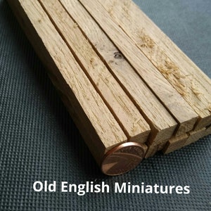 May include: A stack of eight wooden dowels, approximately 1/2 inch in diameter, with a penny for scale.  Old English Miniatures.