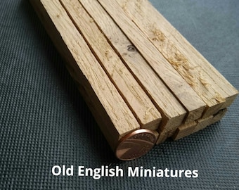 May include: A stack of eight wooden dowels, approximately 1/2 inch in diameter, with a penny for scale.  Old English Miniatures.