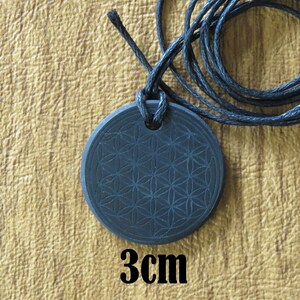 May include: Black pendant necklace with a flower of life design. The pendant is 3 cm in diameter and is on a black cord.