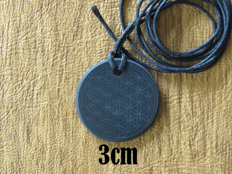 May include: Black pendant necklace with a flower of life design. The pendant is 3 cm in diameter and is on a black cord.