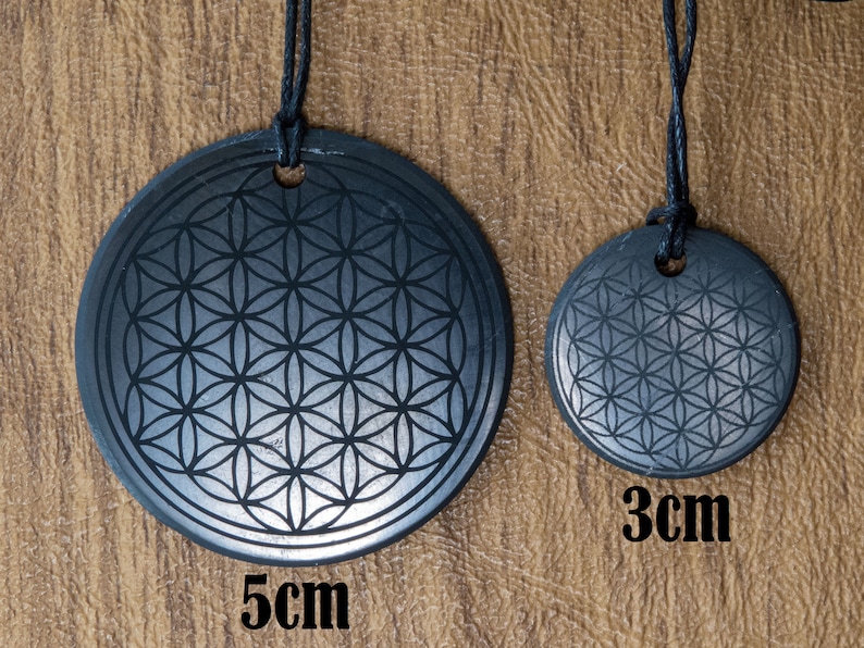 May include: Two black stone pendants with a flower of life design. The larger pendant is 5 cm in diameter and the smaller pendant is 3 cm in diameter.