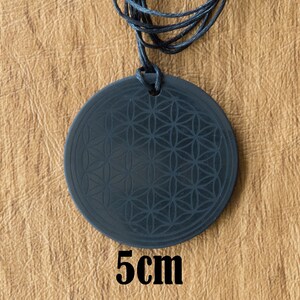 May include: Black pendant necklace with a flower of life design. The pendant is 5 cm in diameter.