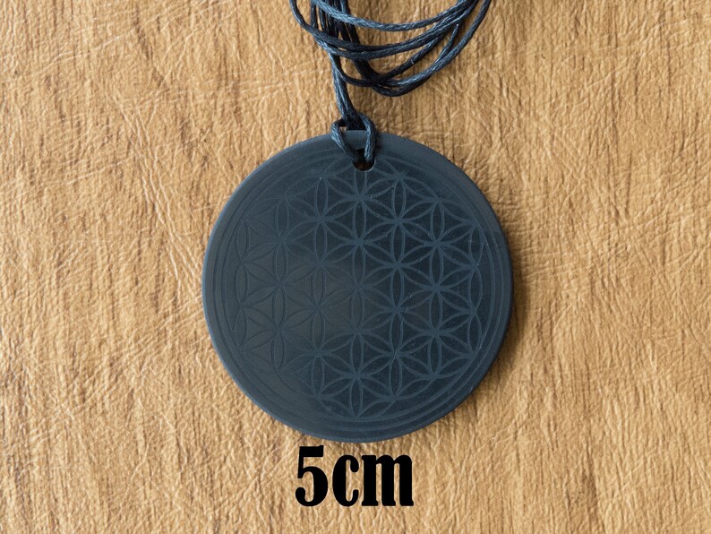 May include: Black pendant necklace with a flower of life design. The pendant is 5 cm in diameter.
