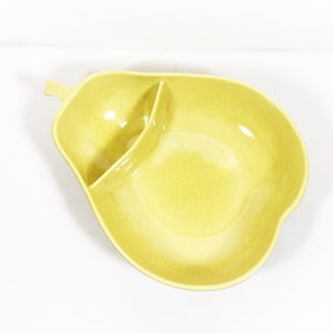 May include: A yellow ceramic serving dish shaped like a pear with two sections. The larger section is a bowl and the smaller section is a dip dish.