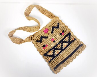 May include: A crocheted bag with a brown strap and black and pink geometric designs.