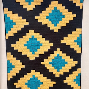May include: A black and yellow quilt with a geometric pattern of diamonds. The diamonds are outlined in yellow and filled with a blue and white pattern.