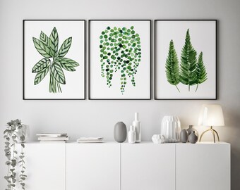May include: Three framed watercolour prints of green plants. The prints are hung on a white wall above a white cabinet with a grey vase and other decorative items on top. The cabinet is sitting on a wooden floor.