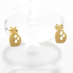 Op de afbeelding: Een paar gouden oorbellen in de vorm van een ananas. De oorbellen zijn klein en delicaat en hebben een eenvoudig, modern ontwerp.