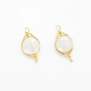 May include: Two gold wire wrapped pendants with clear moonstone cabochons. The pendants are designed with a twisted wire design and have a loop at the bottom for attaching to a chain or cord.