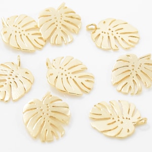 May include: Ten gold-colored metal charms shaped like monstera leaves. The charms have a hole at the top for attaching to jewelry or other crafts.