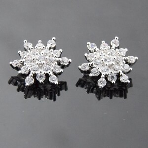 May include: A pair of silver snowflake earrings with clear cubic zirconia stones.