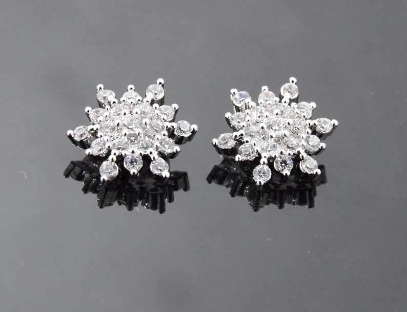 May include: A pair of silver snowflake earrings with clear cubic zirconia stones.