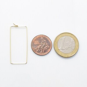 May include: Gold rectangle hoop earrings, shown next to a US penny and a Euro coin for size comparison.