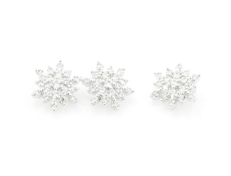 May include: A pair of silver snowflake earrings with clear cubic zirconia stones.
