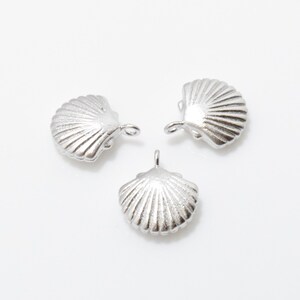 May include: Three silver seashell charms with a loop for attaching to jewelry or other crafts.