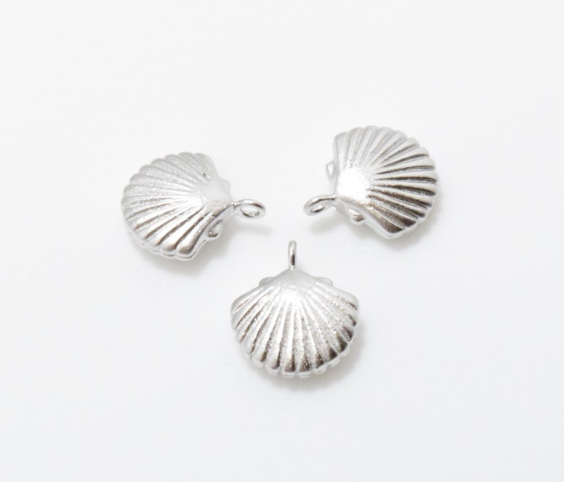 May include: Three silver seashell charms with a loop for attaching to jewelry or other crafts.