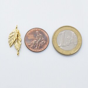 Pode incluir: Pingente de folha de metal dourado com superf&iacute;cie texturizada. O charme &eacute; aproximadamente do tamanho de uma moeda de um centavo de d&oacute;lar americano.