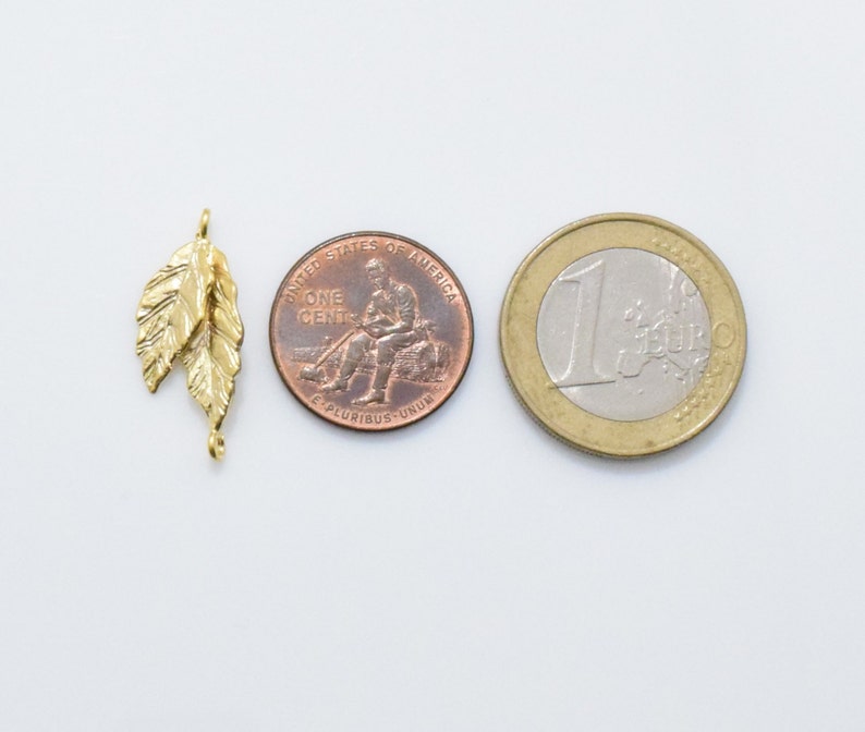 Pode incluir: Pingente de folha de metal dourado com superf&iacute;cie texturizada. O charme &eacute; aproximadamente do tamanho de uma moeda de um centavo de d&oacute;lar americano.