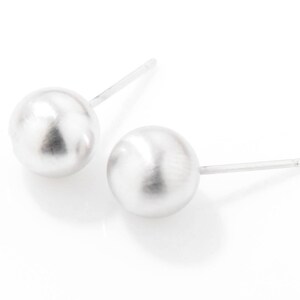 May include: A pair of silver stud earrings with round, smooth, white pearl-like balls.