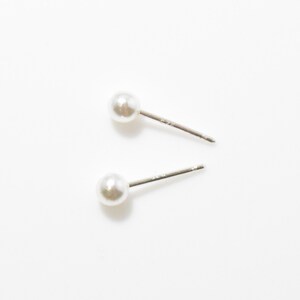 May include: A pair of simple pearl stud earrings with silver posts.