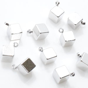 May include: Ten silver cube charms with a loop at the top for attaching to jewellery or other crafts.
