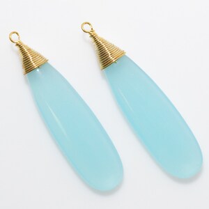May include: A pair of light blue teardrop-shaped earrings with gold wire wrapped around the top of each earring.